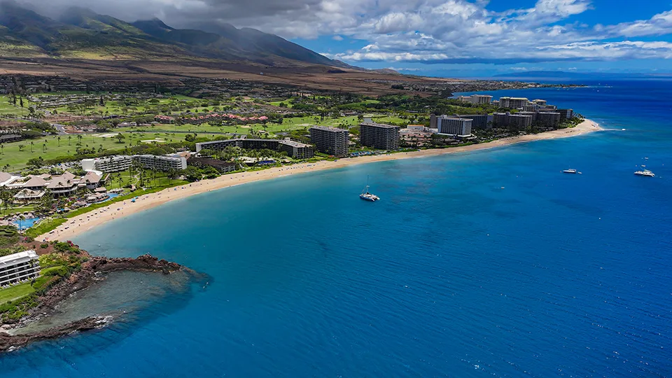 Snorkelers enjoying the clear waters around Black Rock Beach at Ka'anapali, Maui, with rocky outcrops and vibrant coral reefs.
