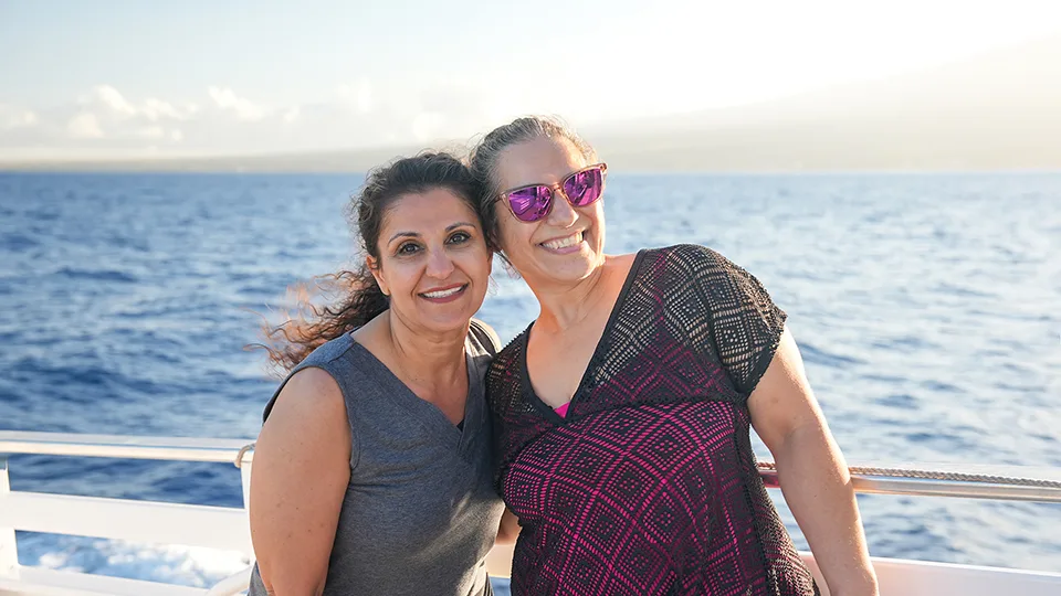 Two Papi's Ohana team members smiling on the deck of Pride of Maui 'Elua