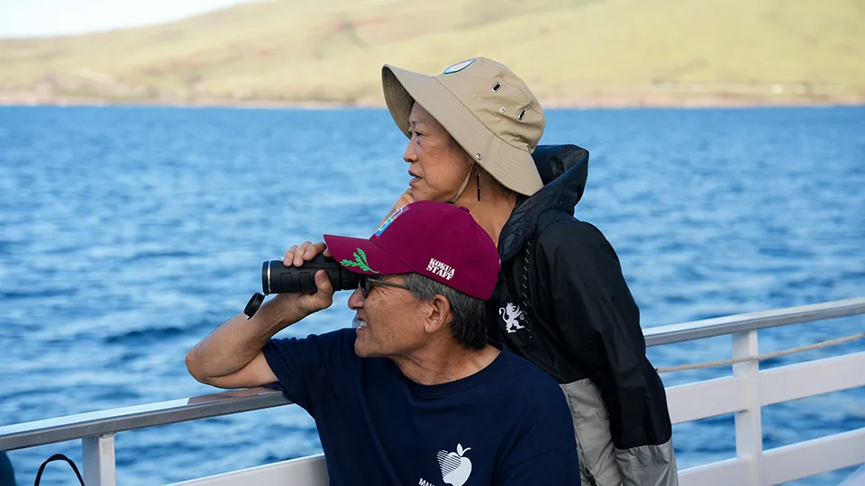 Two Maui Food Bank volunteers watch humpback whales from Pride of Maui 'Elua