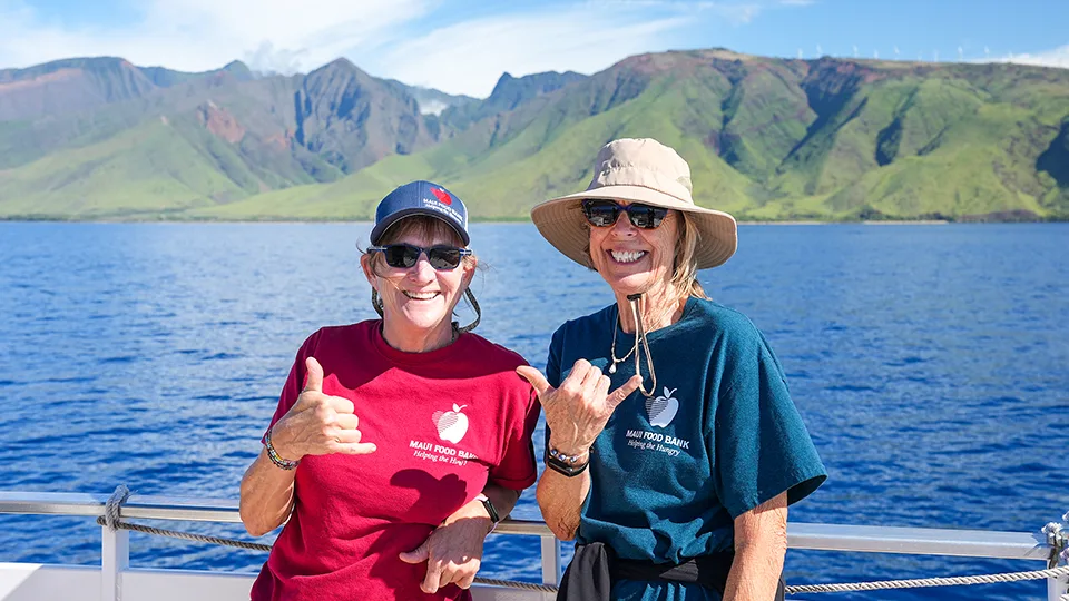 Maui Food Bank volunteers smiling and posing with West Maui mountains visible