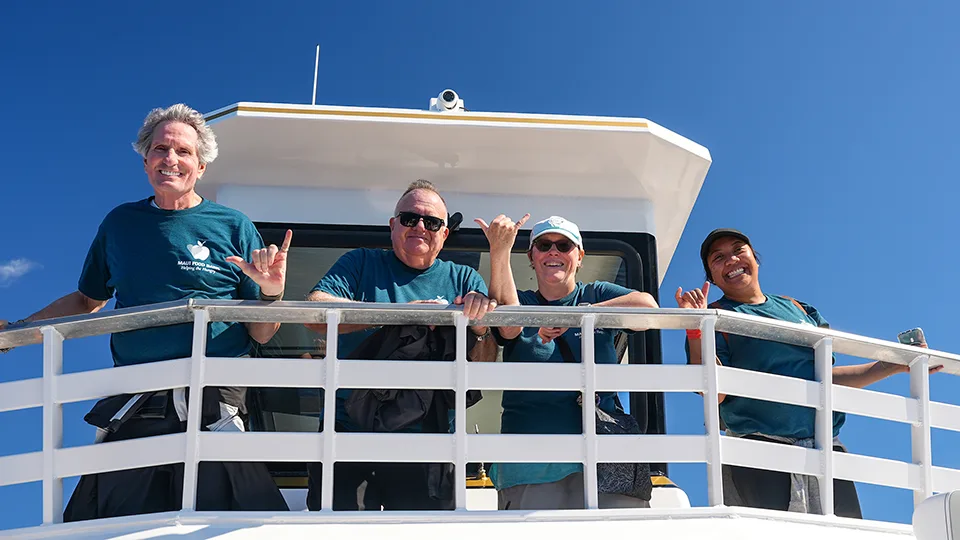 Maui Food Bank team members looking down from Pride of Maui 'Elua's upper deck
