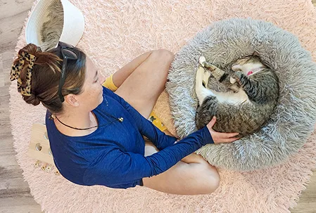 Visitor enjoying therapeutic cuddle session with rescue cat at Cat Cafe Maui in Kahului, showcasing the relaxing cafe experience
