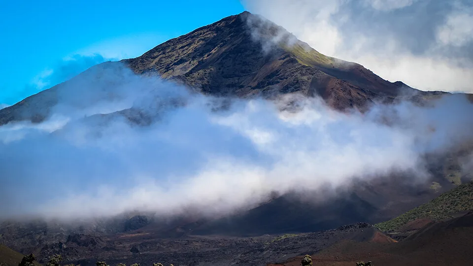 Clouds drifting across Haleakalā’s summit peak, with soft afternoon light highlighting the slopes.