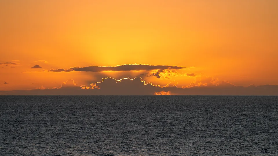 Brilliant orange sunset casting light across the open ocean from Ho‘okipa Beach.