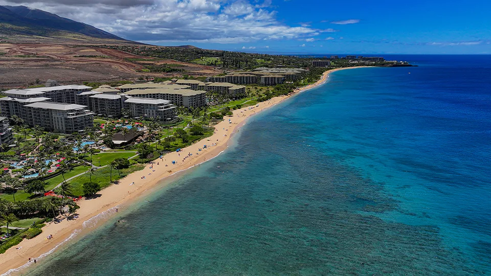 Aerial view of Kāʻanapali Beach lined with resorts and turquoise water.