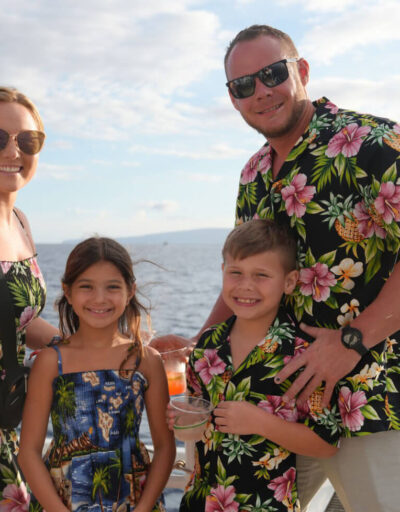 Family wearing aloha attire smiling aboard the Pride of Maui Sunset Dinner Cruise