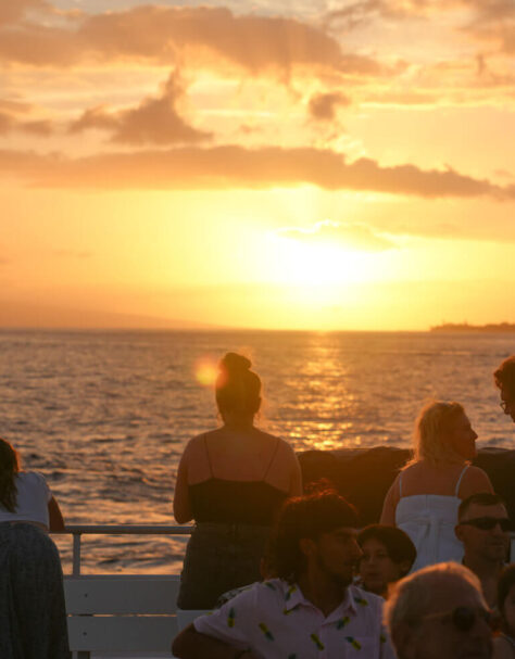 Guests watching the sunset from the open deck of the Pride of Maui catamaran