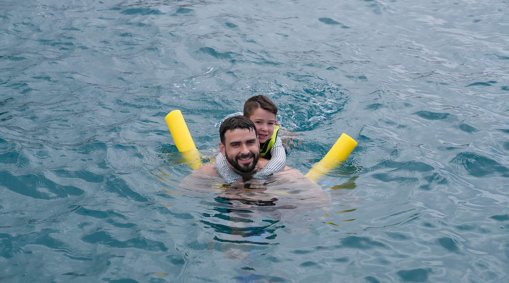 Parent and child floating with noodles during a snorkel stop off Maui.